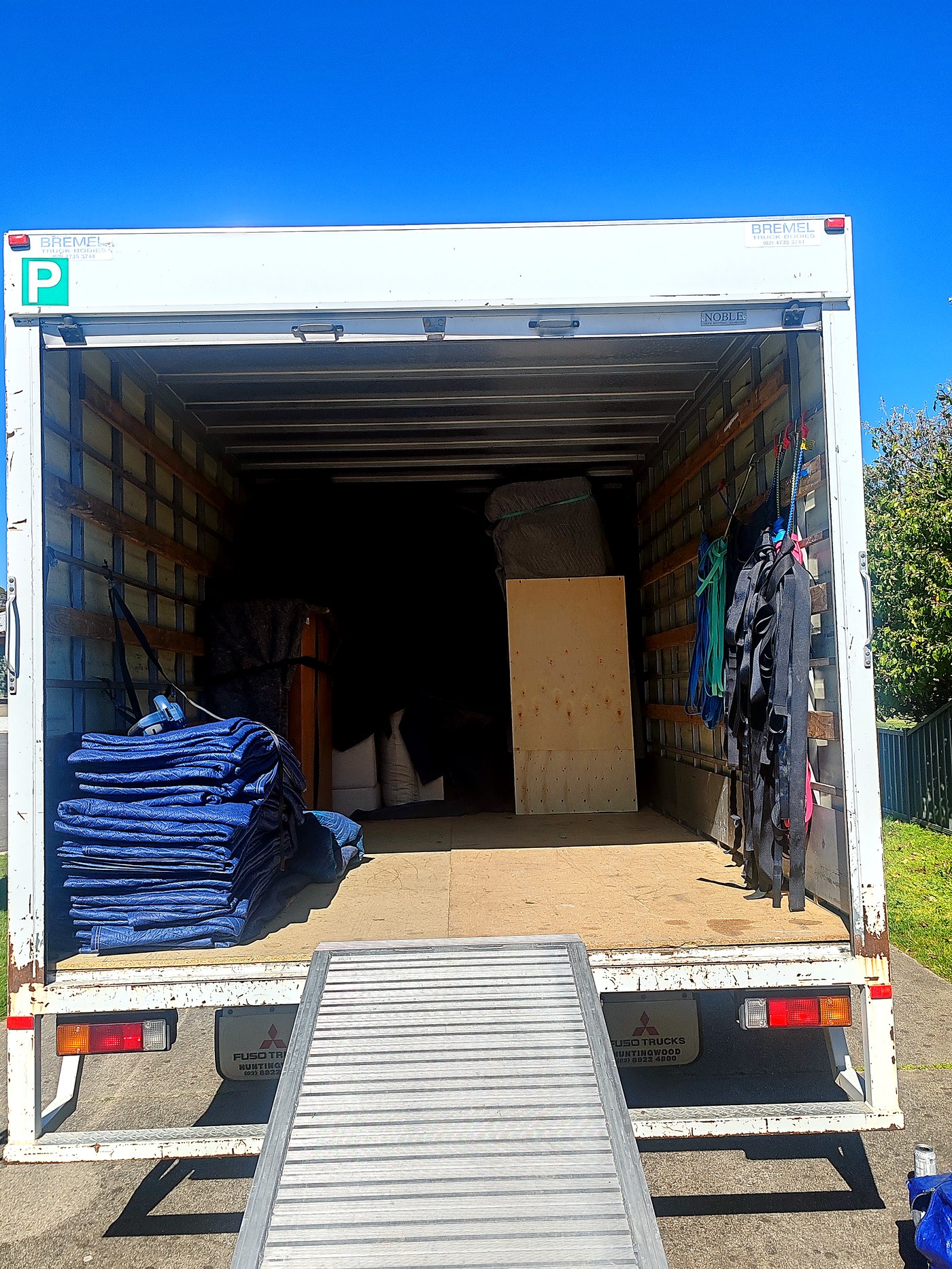 Furniture wrapped in blankets and secured in the back of the removals truck, ramp extended